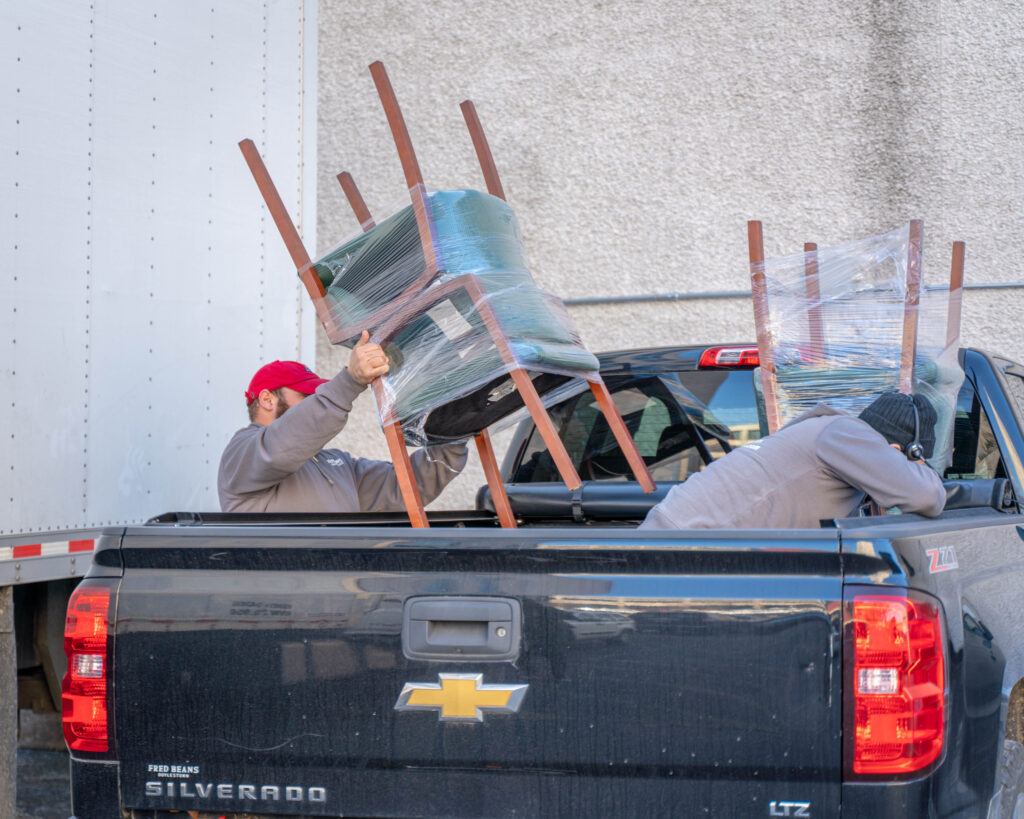 Men loading chairs into truck bed.