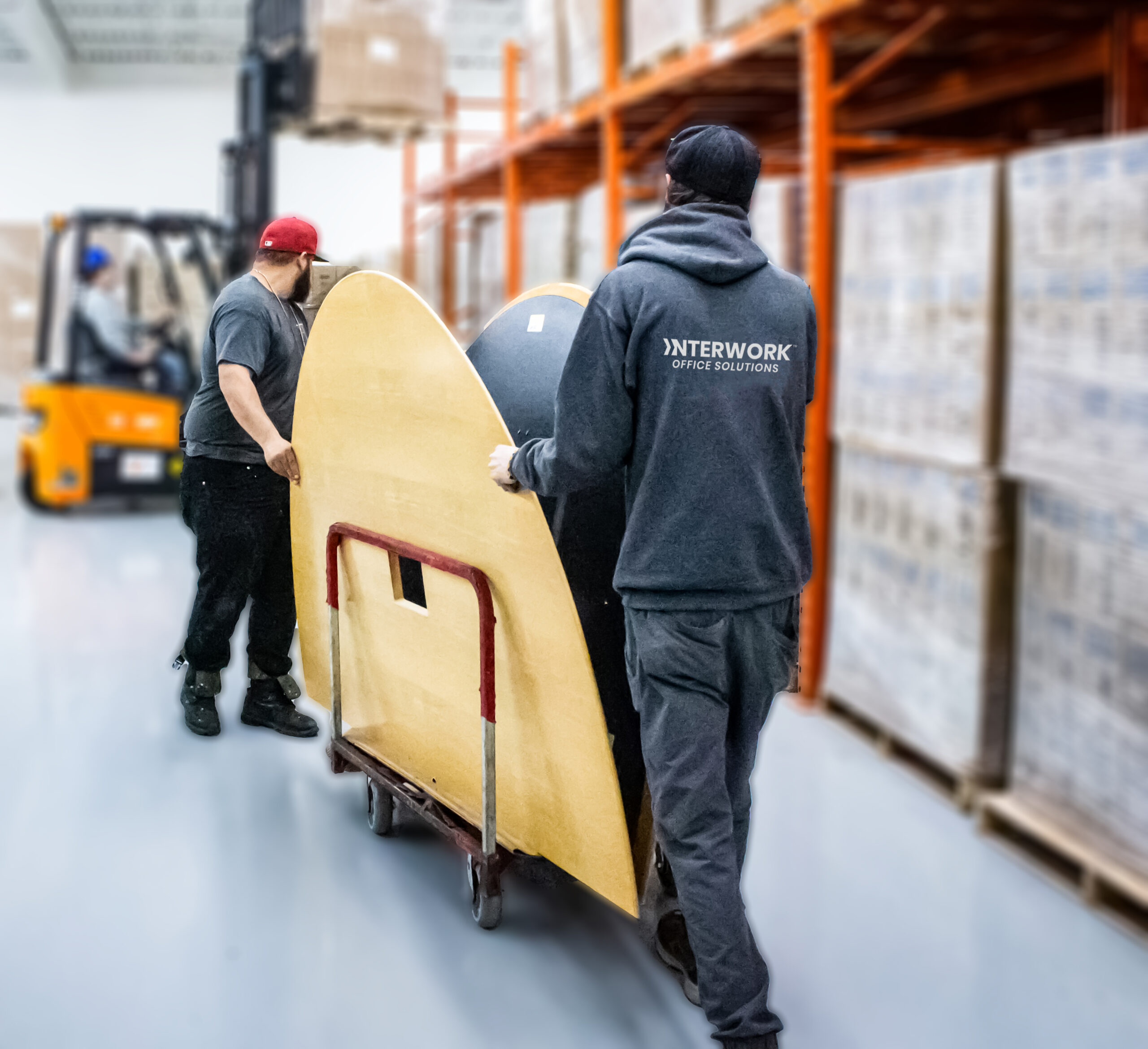 Warehouse workers moving large table.