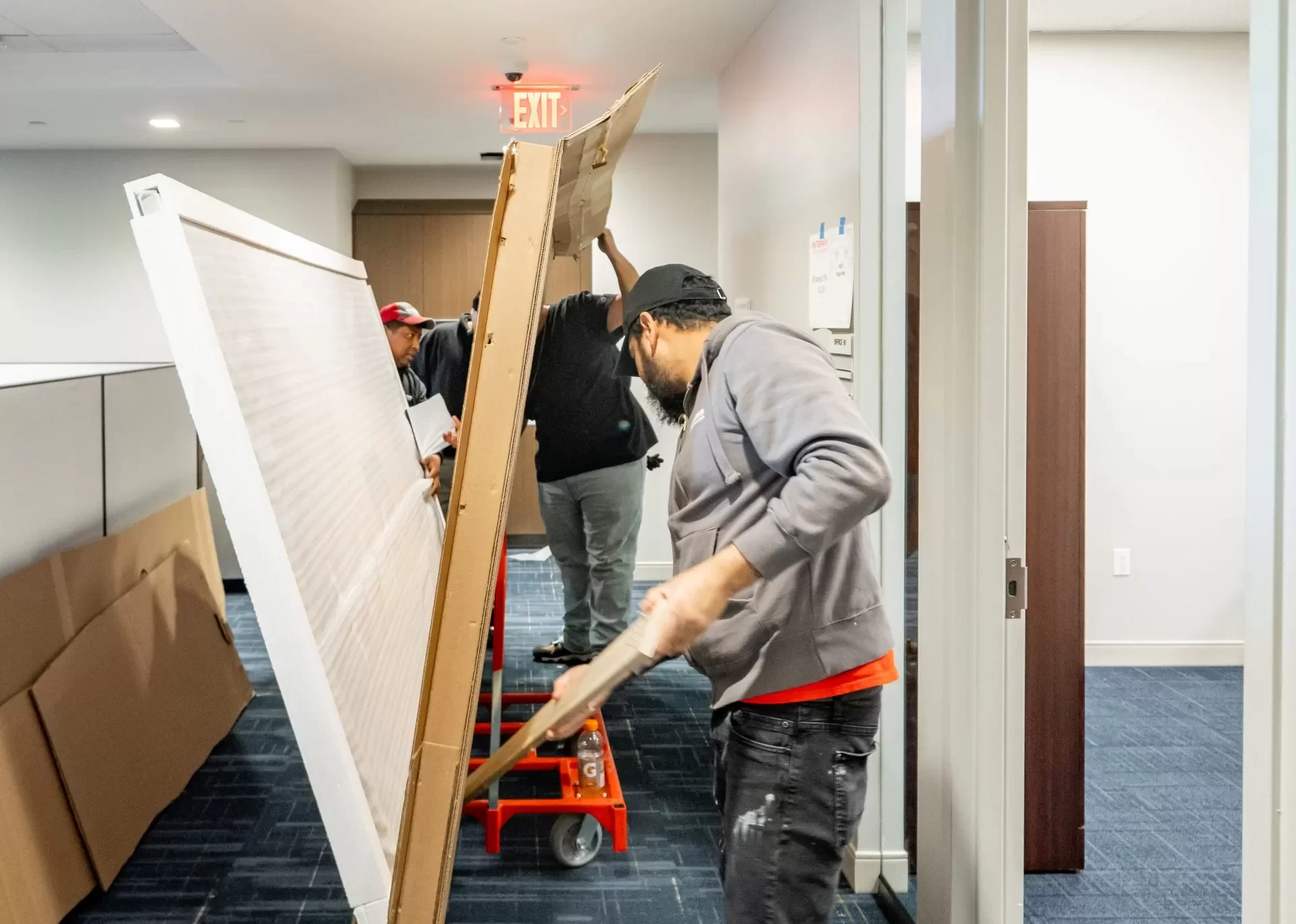Workers moving large office panel.
