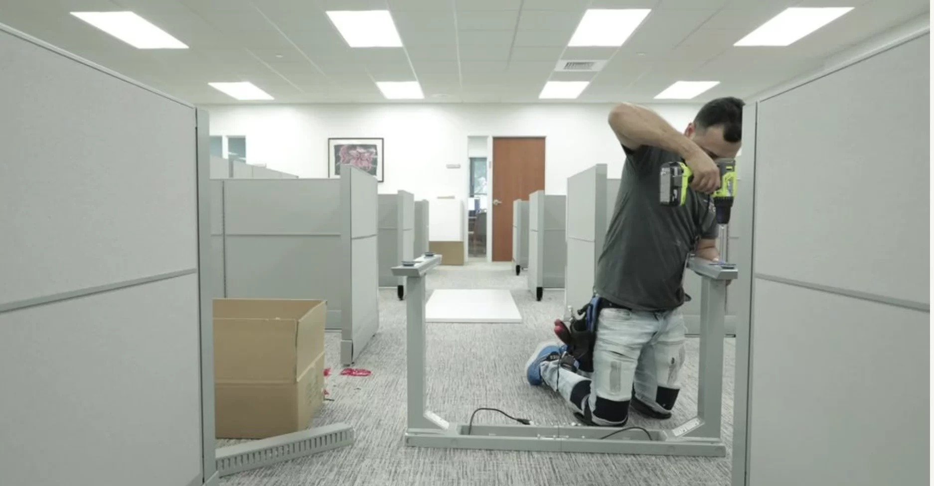 Man assembling office cubicle partitions.